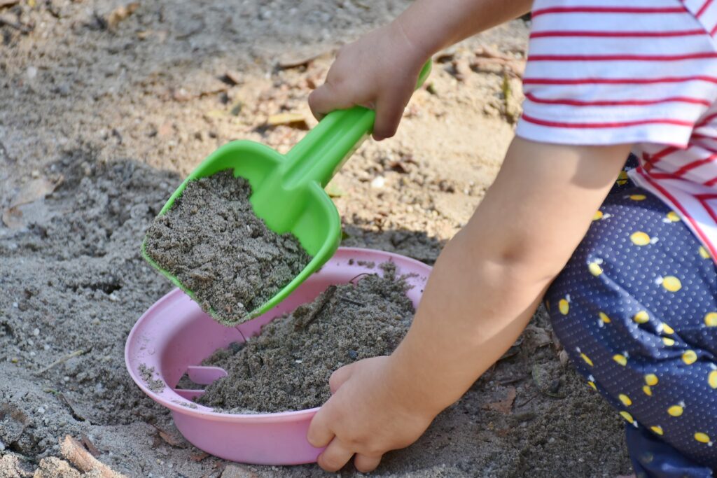 Child's hands playing with sand and a bucket and spade