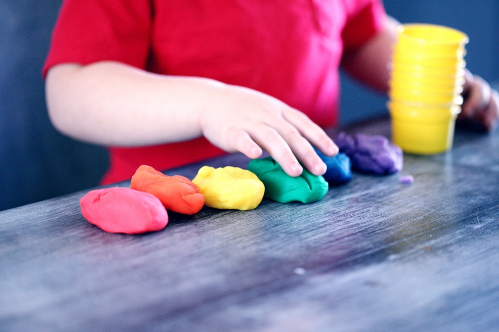 child's hands lining up different coloured playdoh